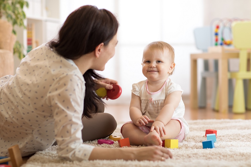 Nanny and Baby Sitting on Floor Playing with Wooden Blocks